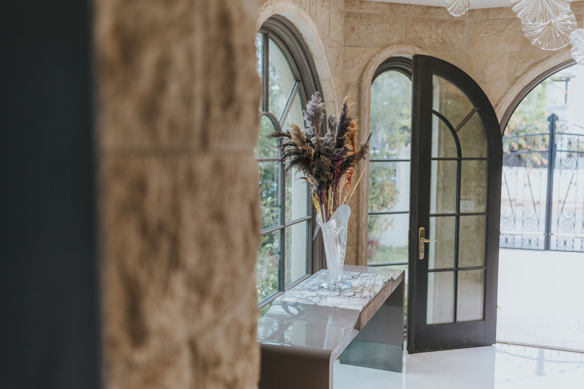 Elegant interior with arched windows and doorway, bouquet on a table.