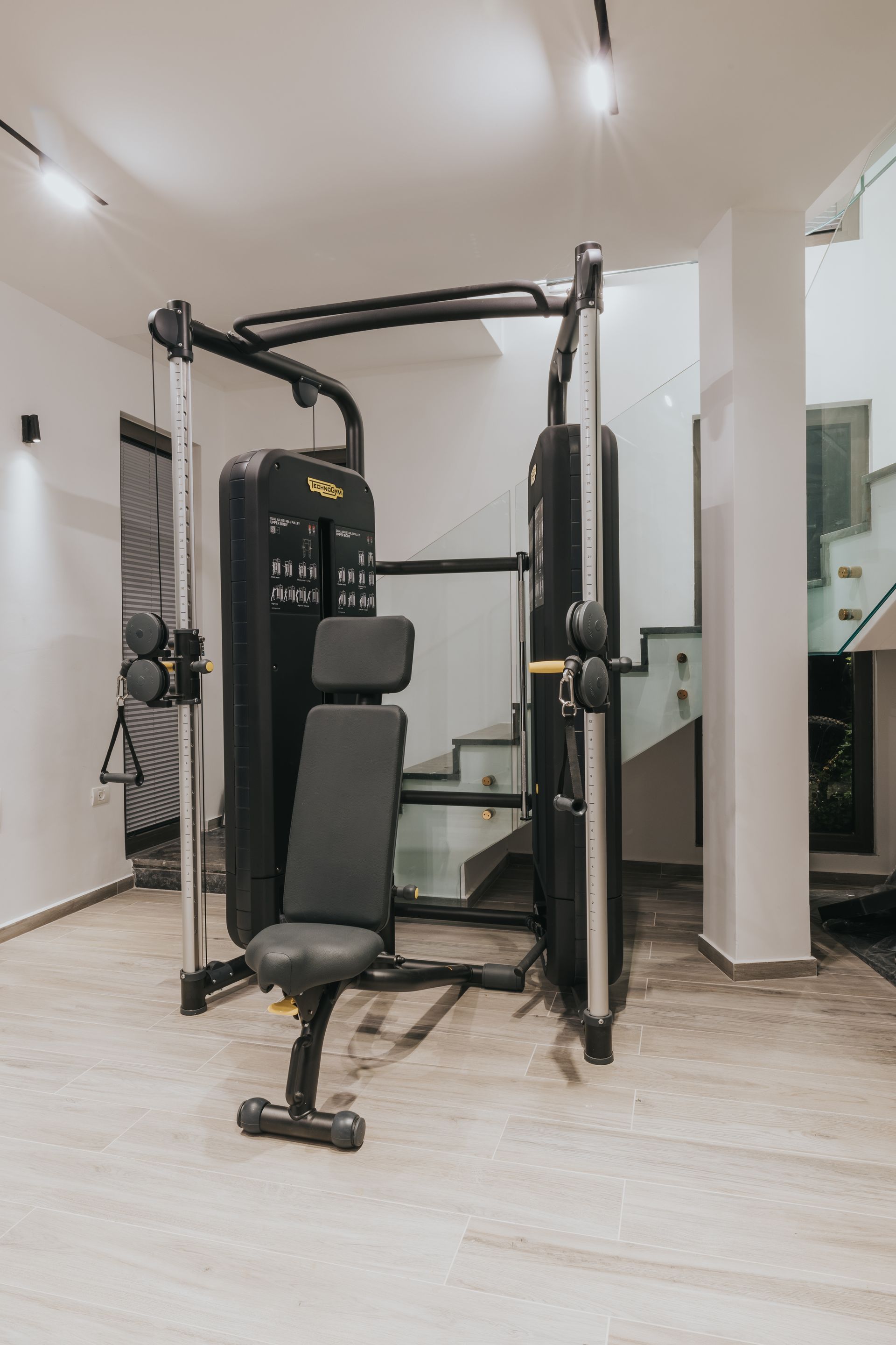 Weight machine in a bright room with stairs in the background.