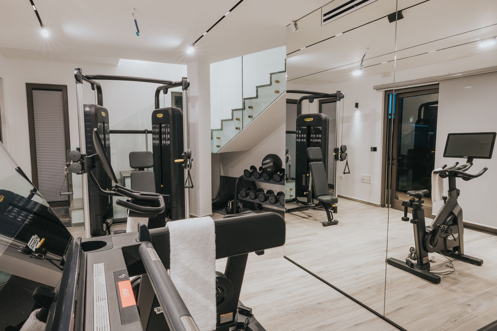 Gym with exercise equipment, including weight machines, a treadmill, weights, and a stationary bike.