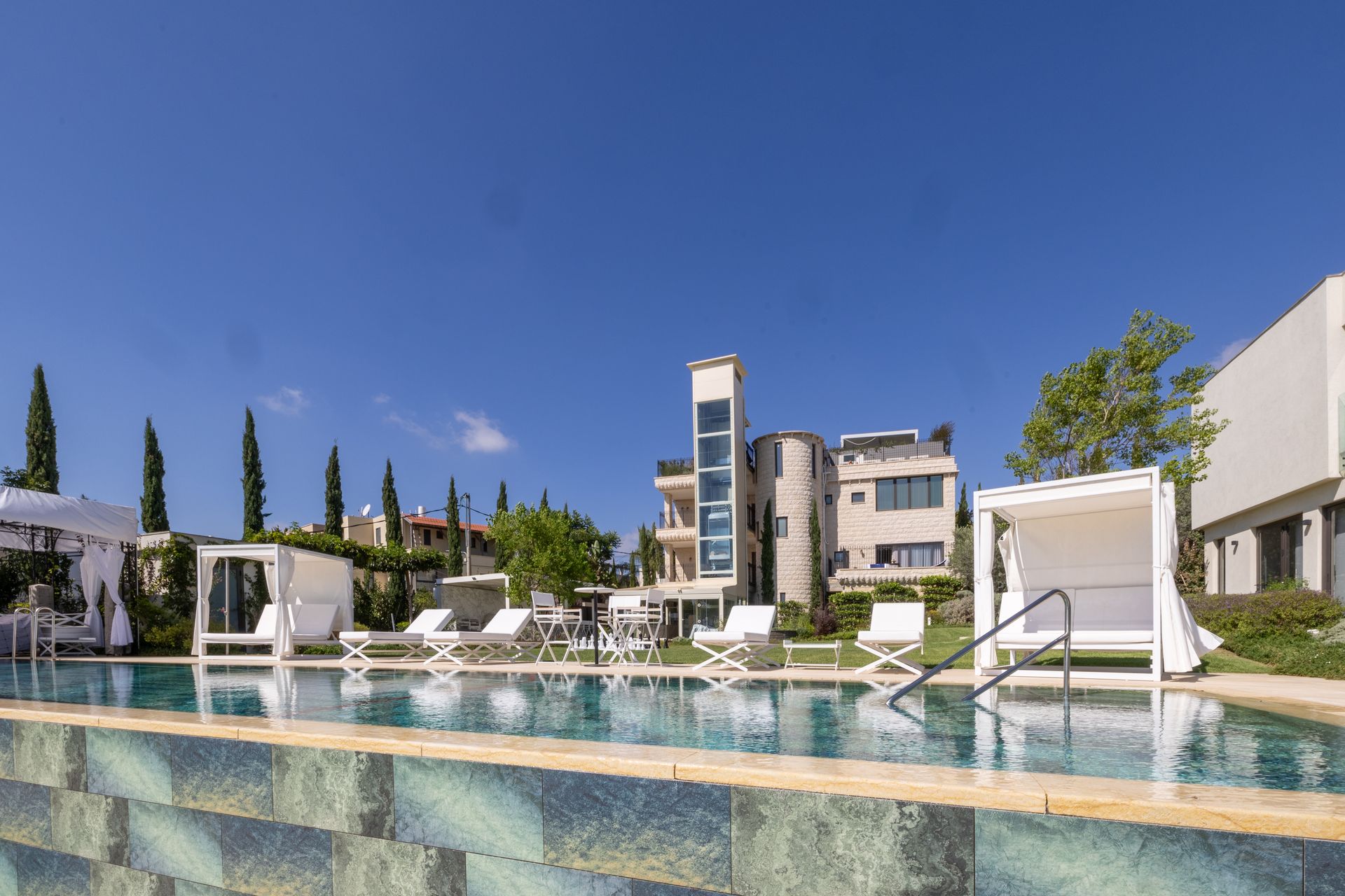 Swimming pool and luxury resort buildings against a bright blue sky.