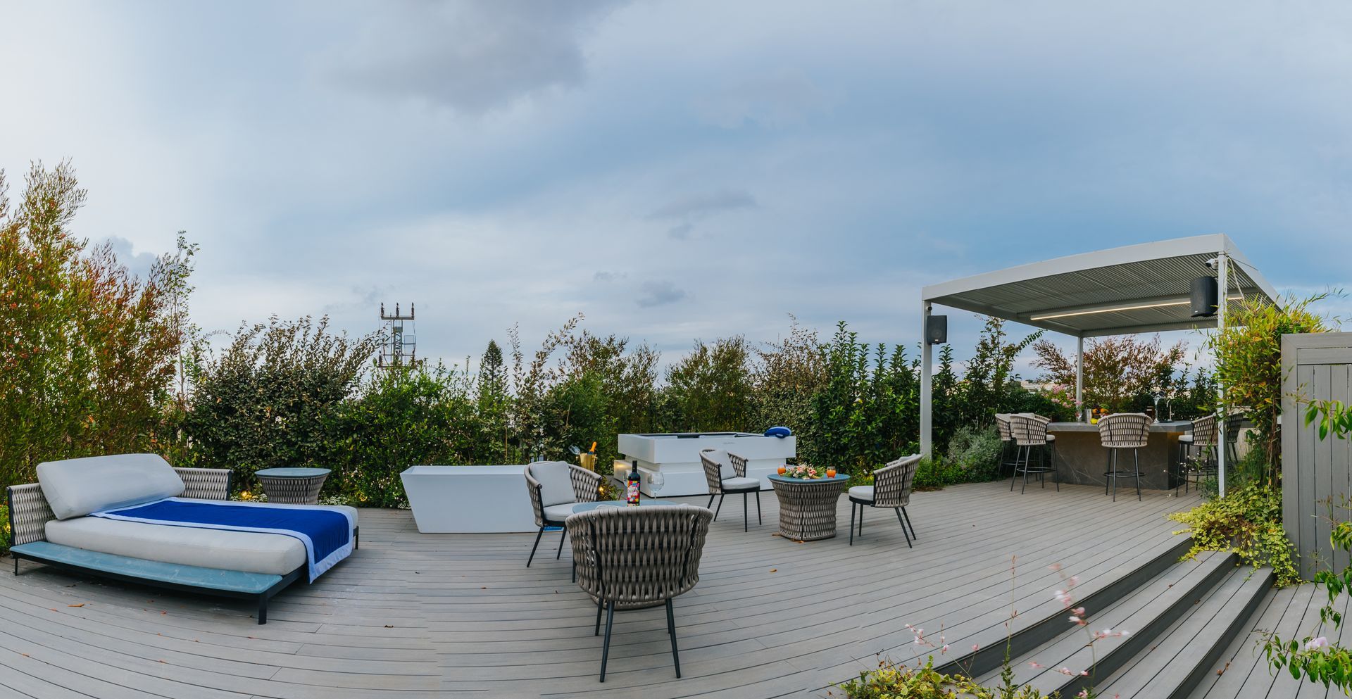 Rooftop patio with seating, dining area, and plants under an overcast sky.