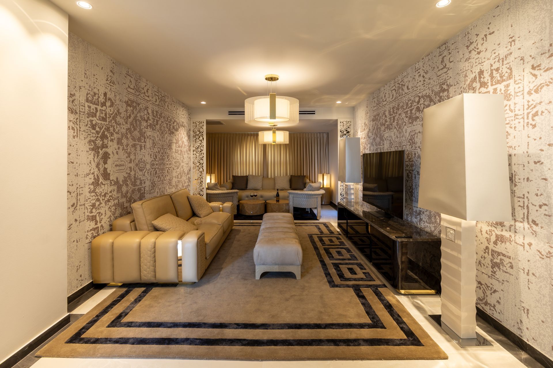 Luxurious living room with beige sofa, patterned rug, and textured wallpaper.