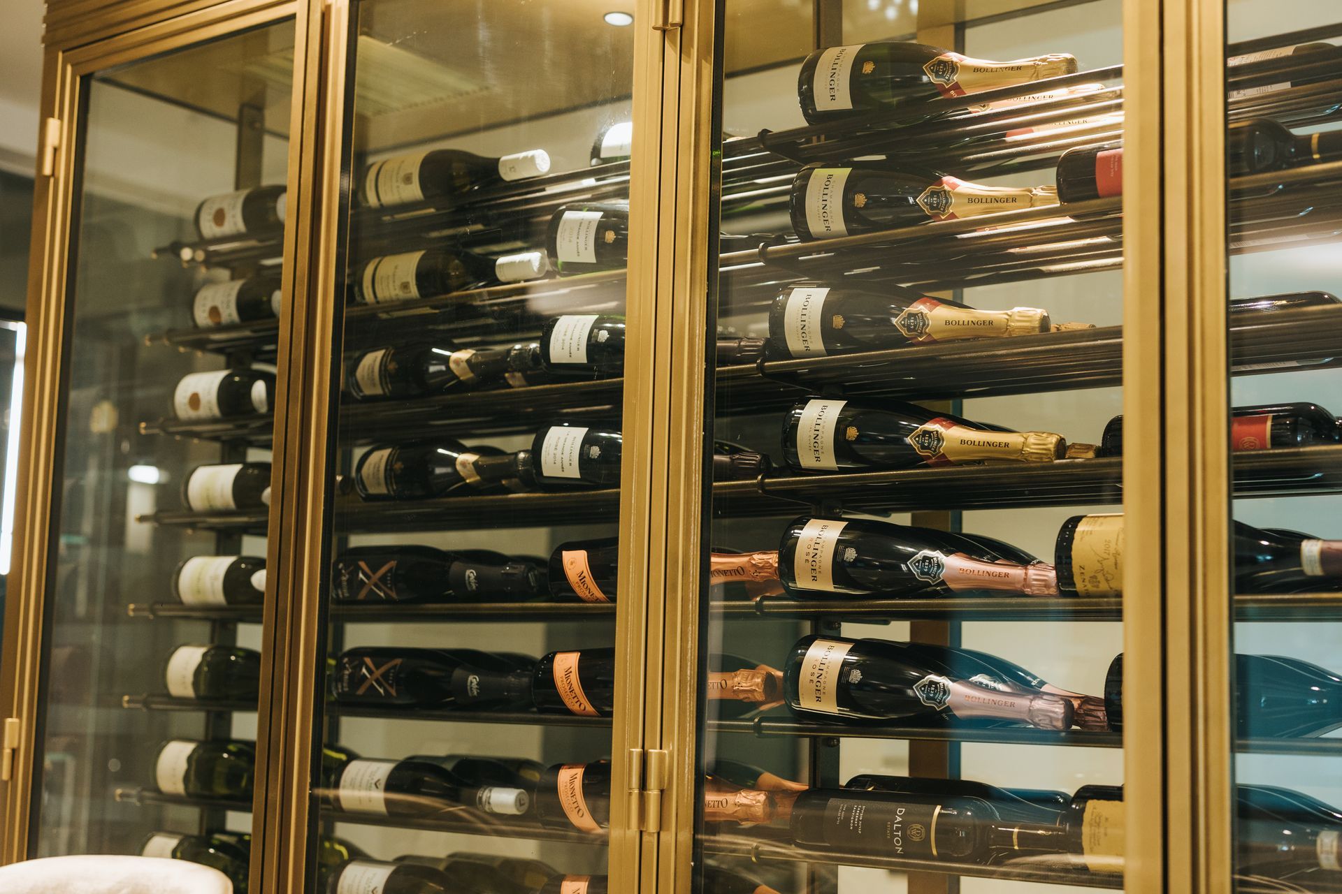 Wine bottles in a glass-door cabinet. The cabinet has a gold frame.