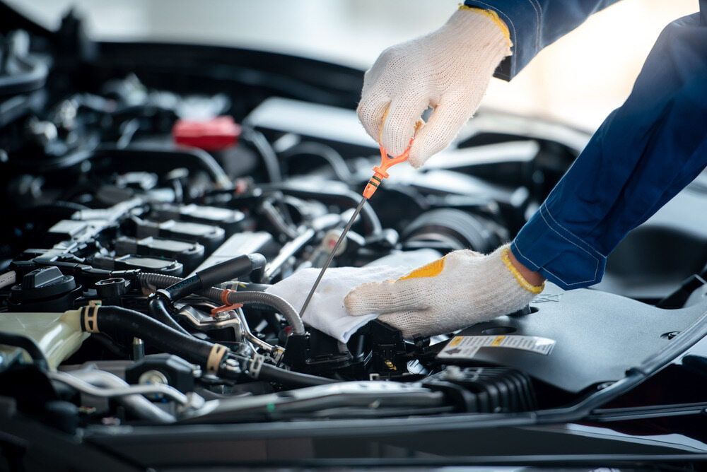 Mechanic Checking Oil With Dipstick in a Car Engine — Burcher EFI & Service Centre in Orange, NSW