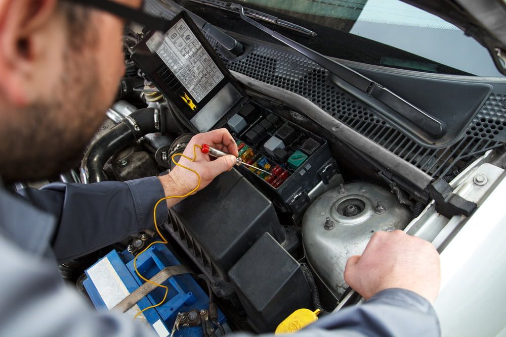 Mechanic Working on a Car Engine, Using a Tool on a Fuse Box — Burcher EFI & Service Centre in Orange, NSW