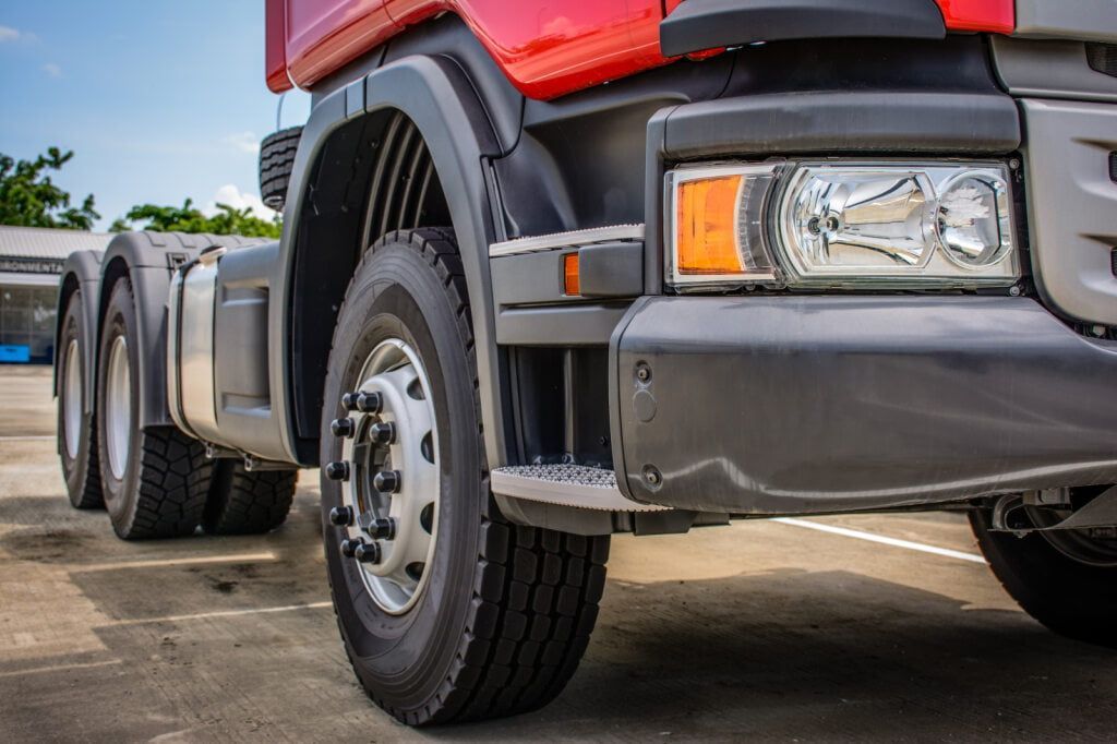 Red and Black Semi-truck Parked Outdoors, Tires and Front End in Close-up — Burcher EFI & Service Centre in Orange, NSW