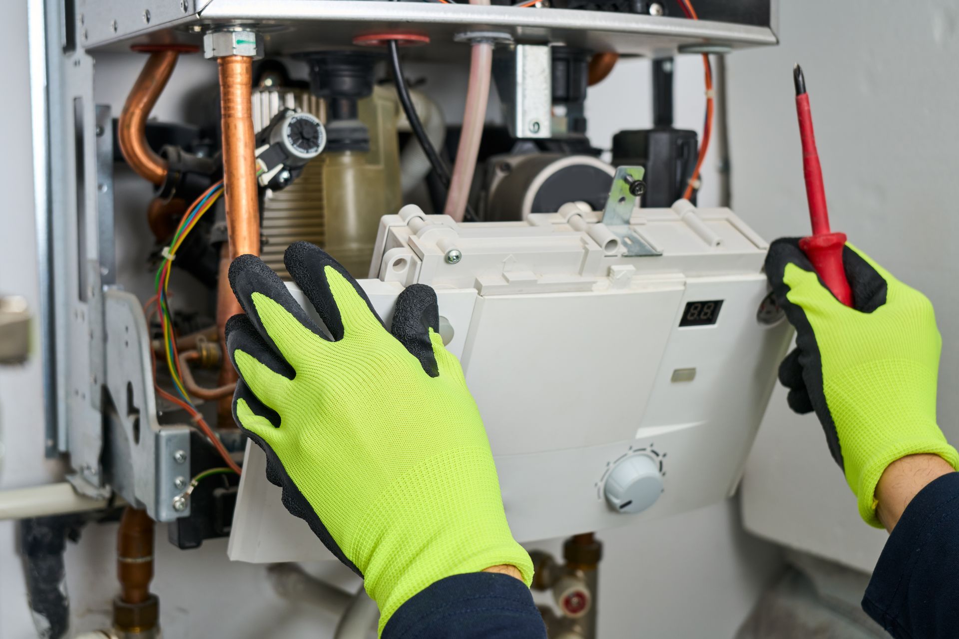 Gloved technician repairing HVAC unit with screwdriver and open panel exposed Gloved technician repairing HVAC unit with screwdriver and open panel exposed
