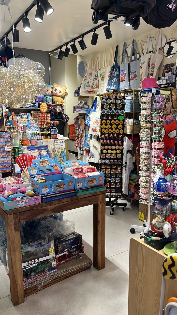 Un negozio di souvenir luminoso e affollato di ninnoli colorati, peluche e articoli appesi sugli scaffali espositivi.