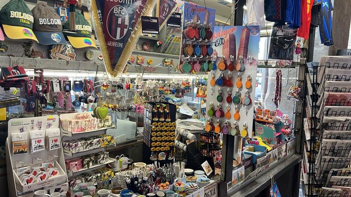 Vetrina colorata di un negozio di souvenir con ninnoli appesi, portachiavi, calamite e scaffali pieni di merce.