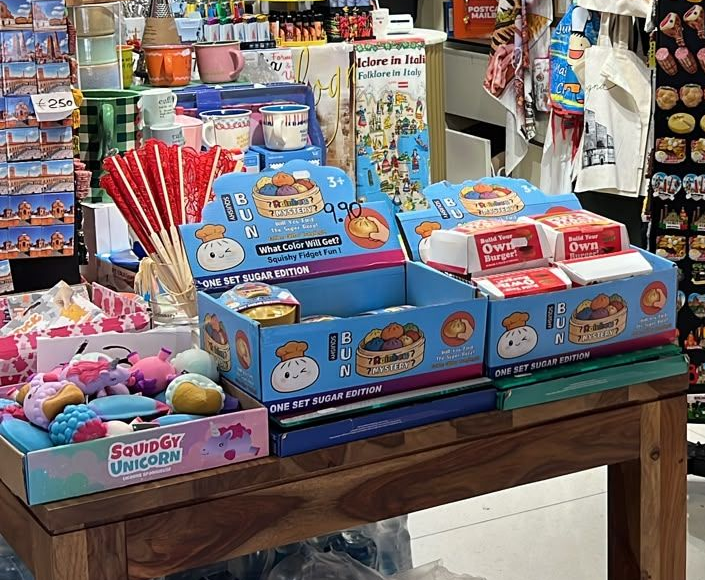 Esposizione di scatole colorate di giocattoli e caramelle su un tavolo di legno in una corsia di un negozio.
