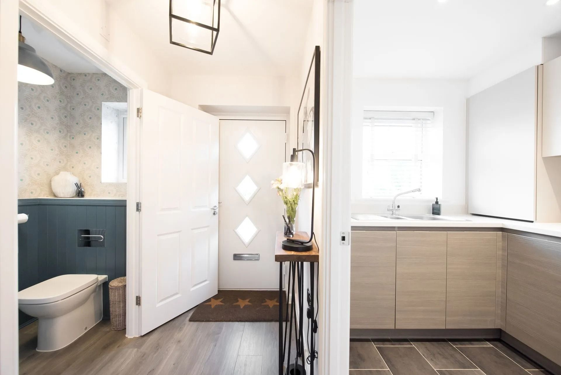 Modern Bathroom Hallway with White Door, Gray Tile Floor, Navy Shower Area, and Light Wood Vanity in Twin Falls, ID