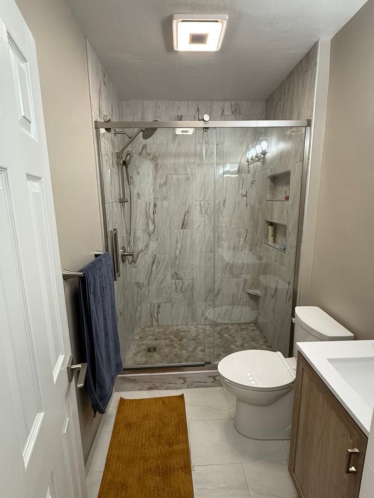 Small Bathroom with A Glass Shower, Toilet, Sink, Towel Rack, and Yellow Rug in Twin Falls, ID