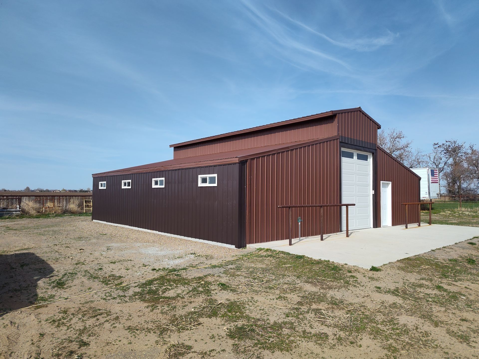 Brown Metal Barn-Style Building on A Concrete Pad in A Grassy Field Under a Blue Sky in Twin Falls, ID