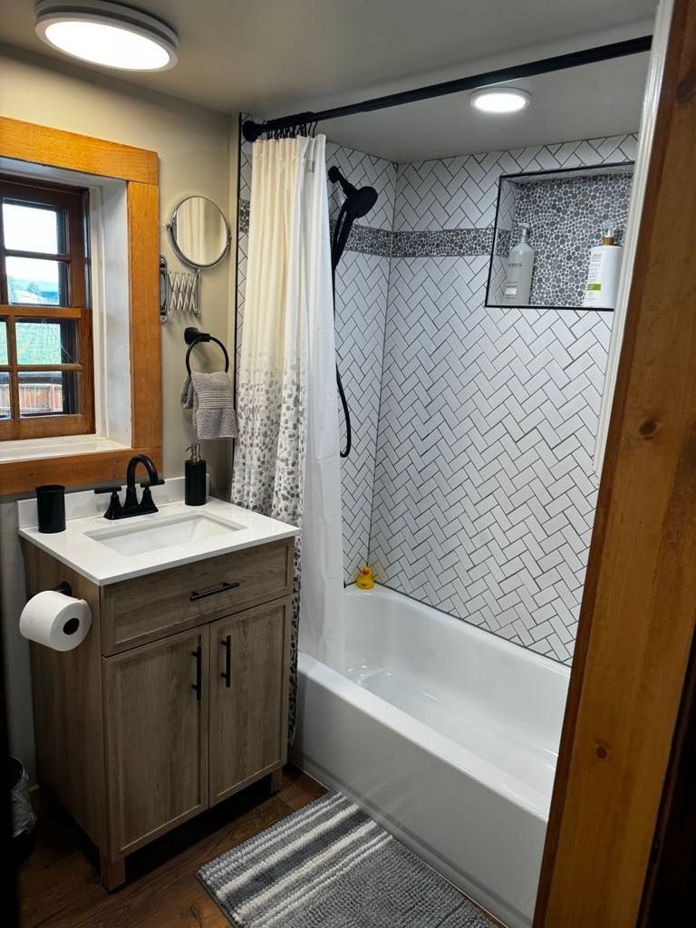 Small Bathroom with A Wood Vanity, Toilet Paper Holder, and White Tub/shower with Patterned Tile in Twin Falls, ID