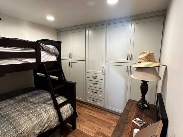 Small Bedroom with Black Bunk Bed, White Built-In Cabinets, Wood Floor, and A Dresser with A Lamp in Twin Falls, ID