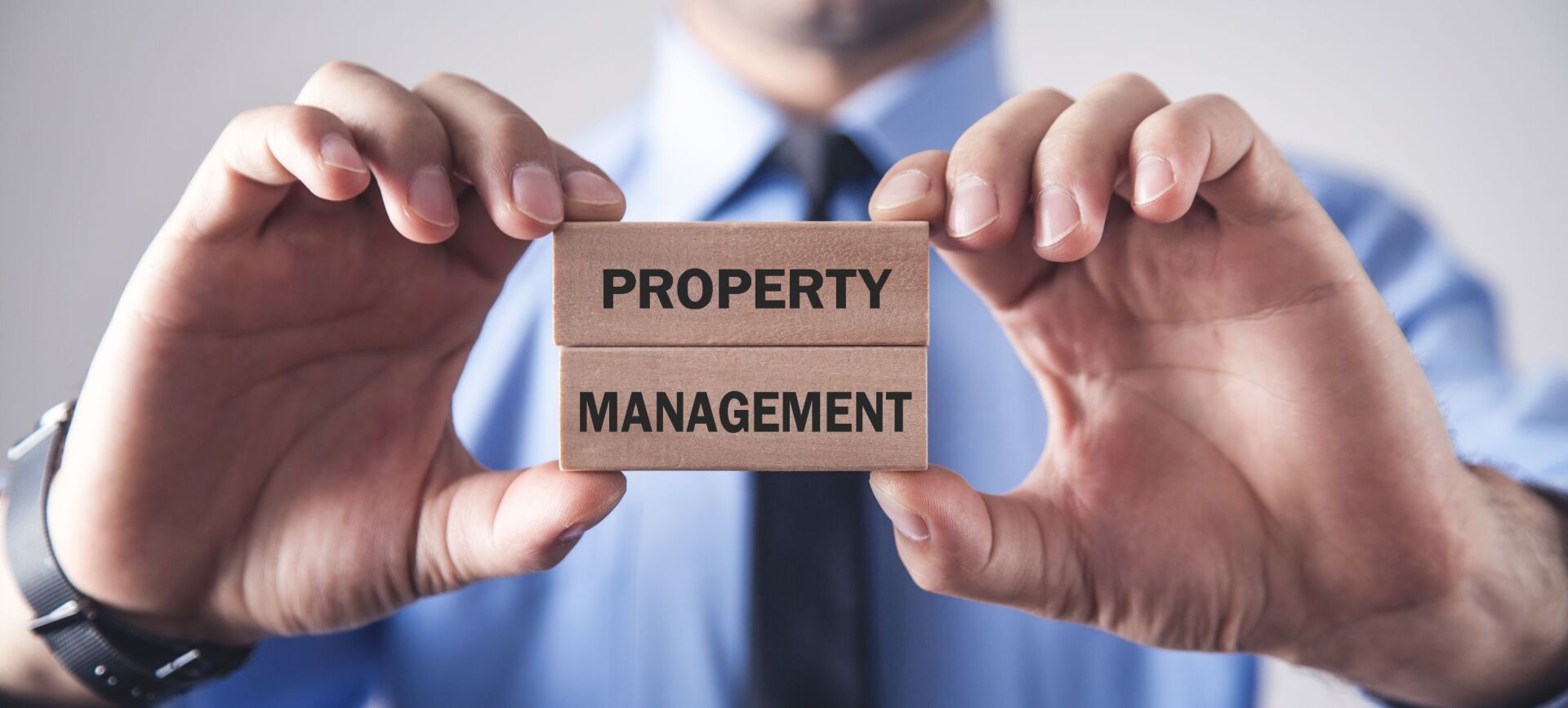 A man is holding two wooden blocks with the words property management written on them.