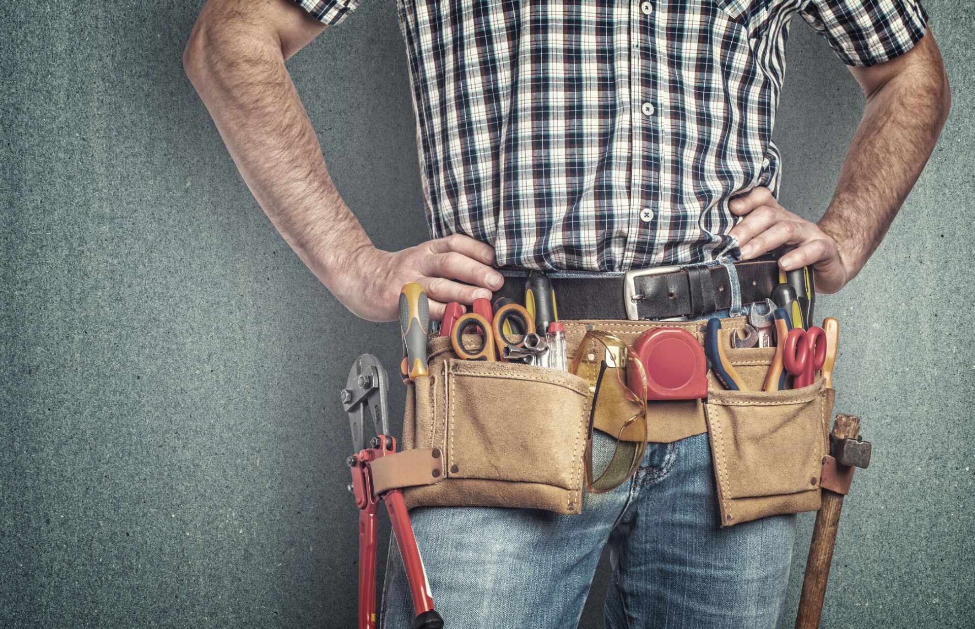 A man is wearing a tool belt with tools in it.