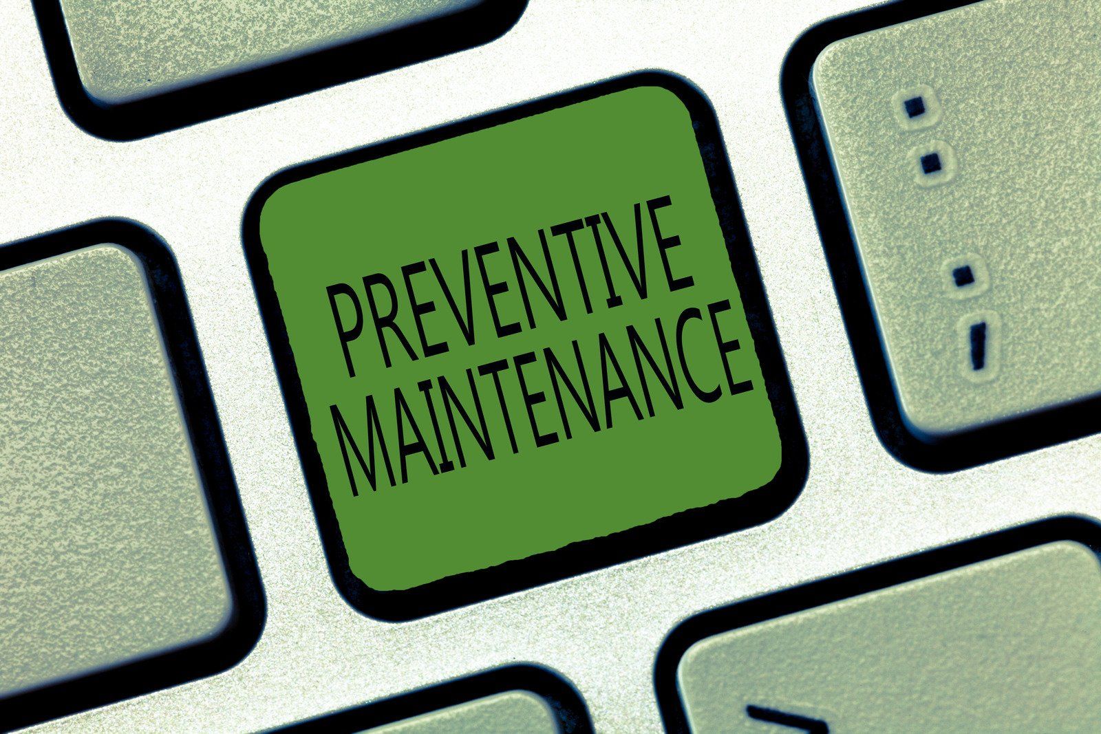 A keyboard with a green button that says preventive maintenance