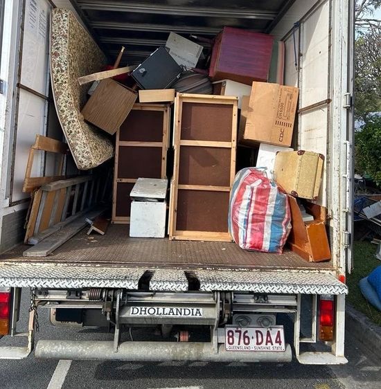 Overloaded moving truck packed with furniture, boxes, and bags in a loading dock