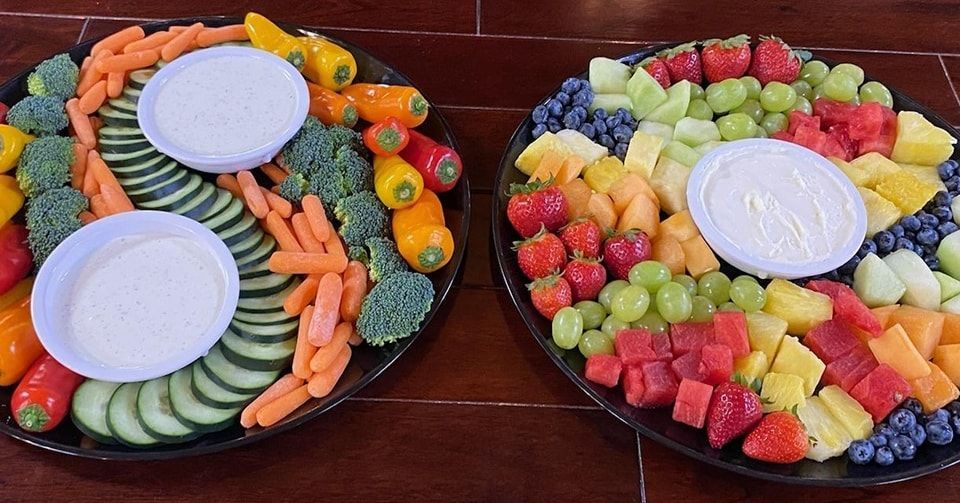 Two trays of fruit and vegetables on a wooden table