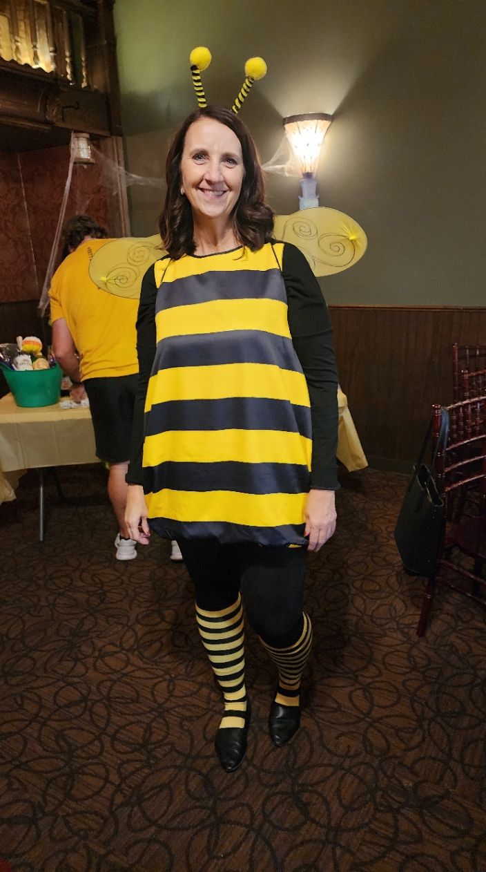 A woman in a bee costume is standing in a room.
