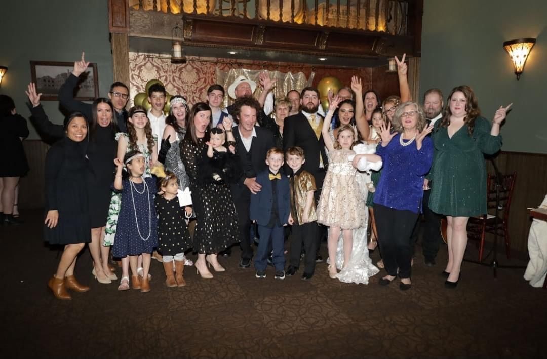 A large group of people are posing for a picture at a wedding reception.