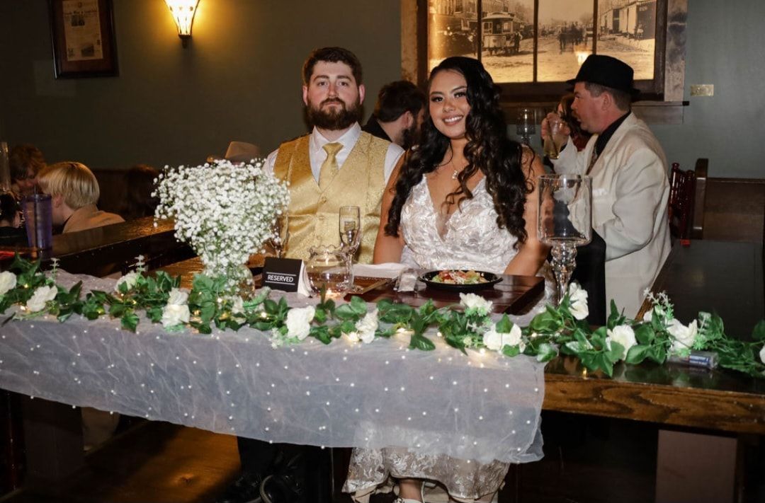 A bride and groom are sitting at a table at a wedding reception.