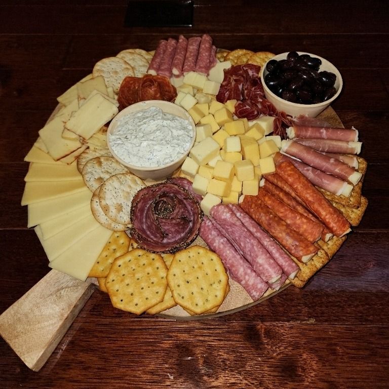 A cheese board with crackers and olives on a wooden table