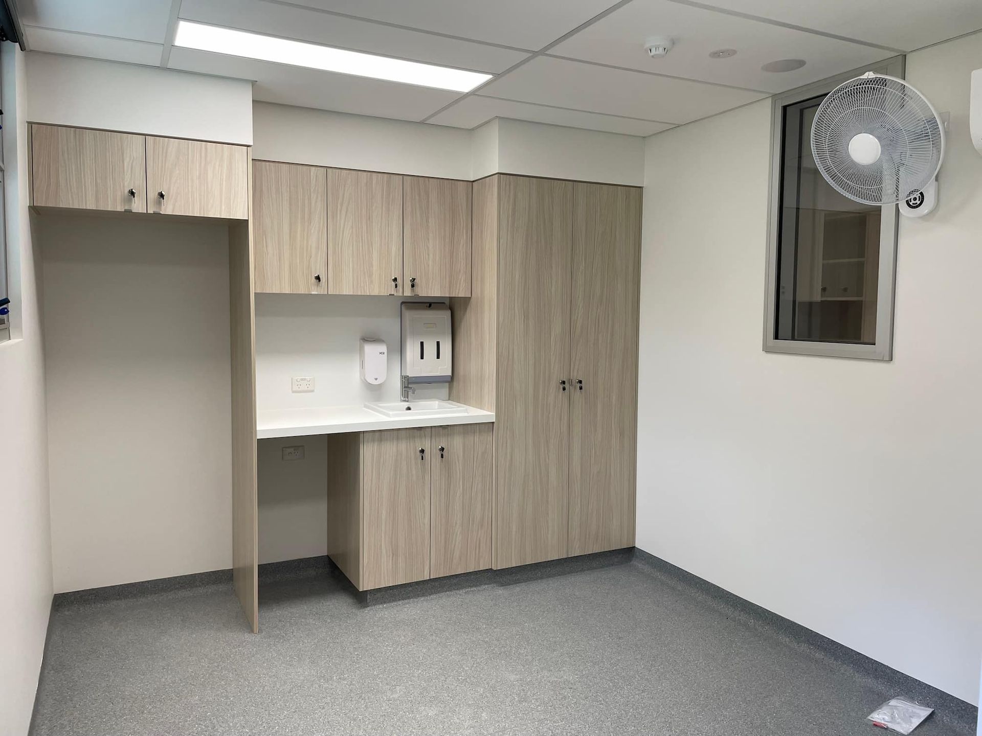 an empty room with cabinets and a fan hanging on the wall
