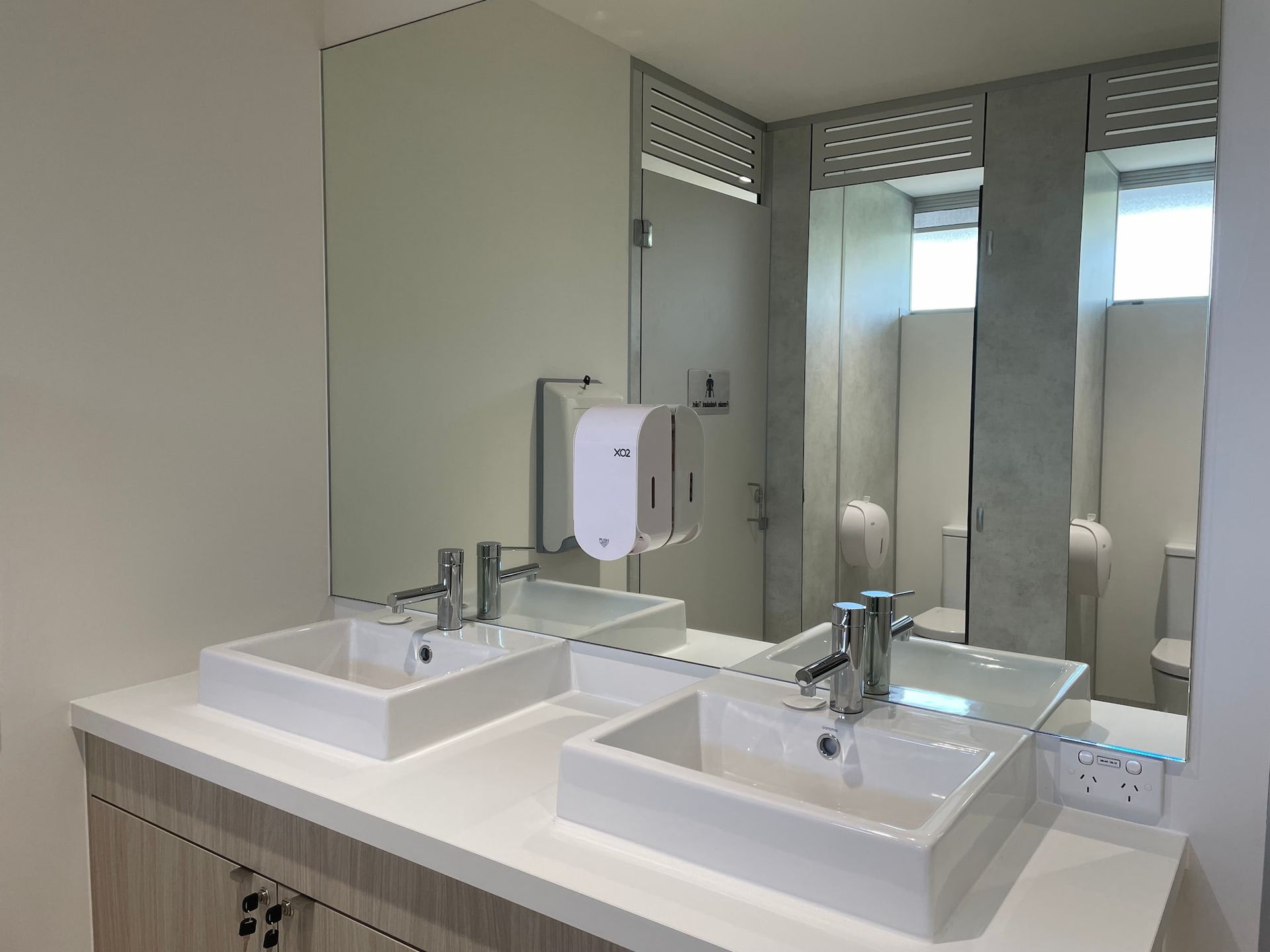 a bathroom with two sinks and a soap dispenser that says ice