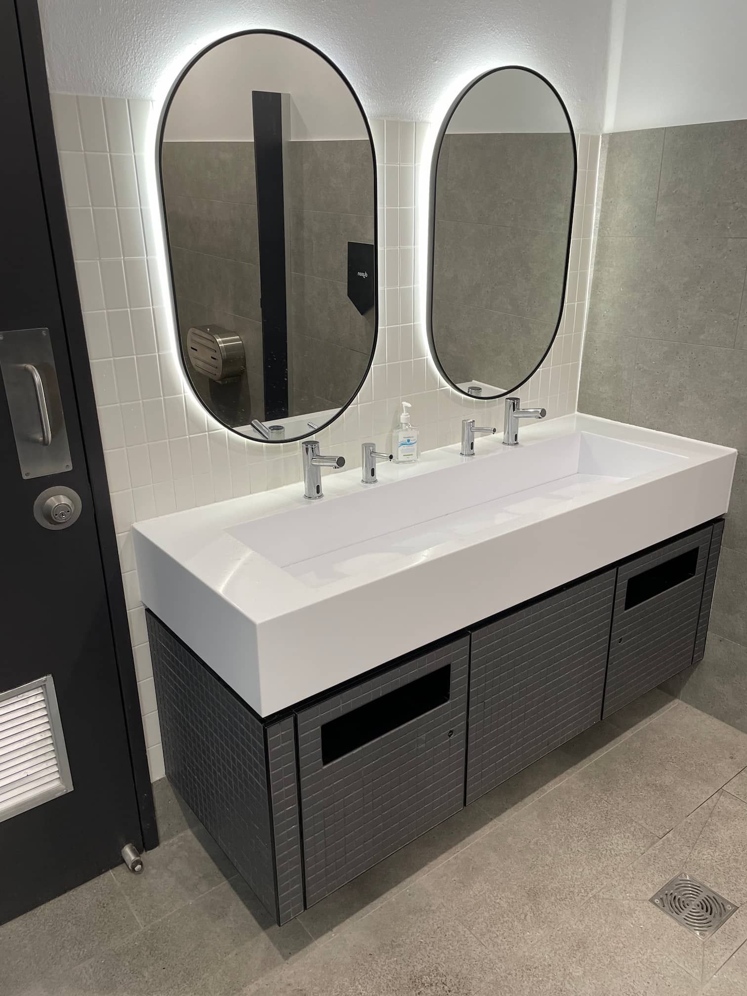 a bathroom sink with two mirrors and a soap dispenser