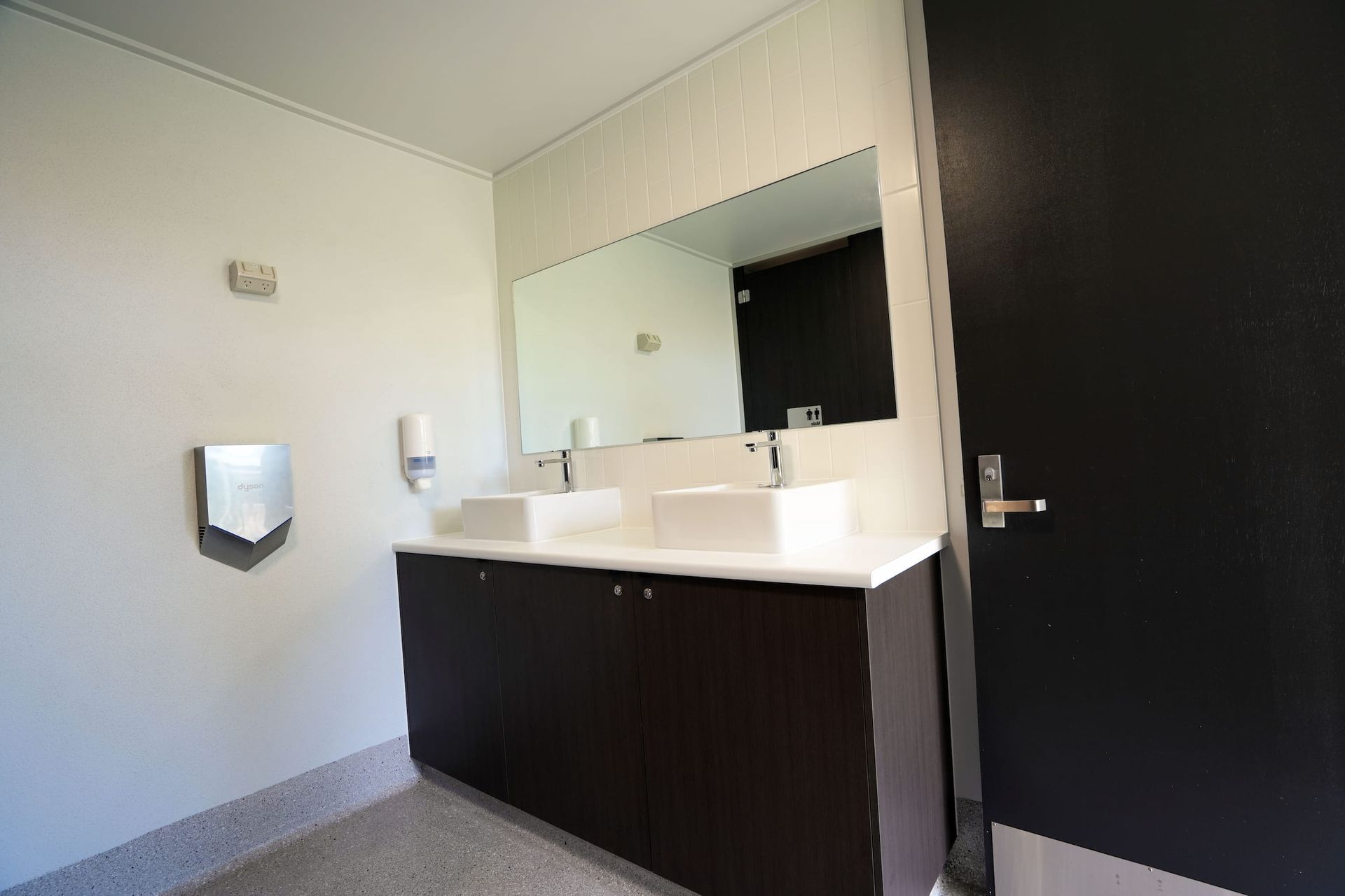 a bathroom with two sinks and a hand dryer