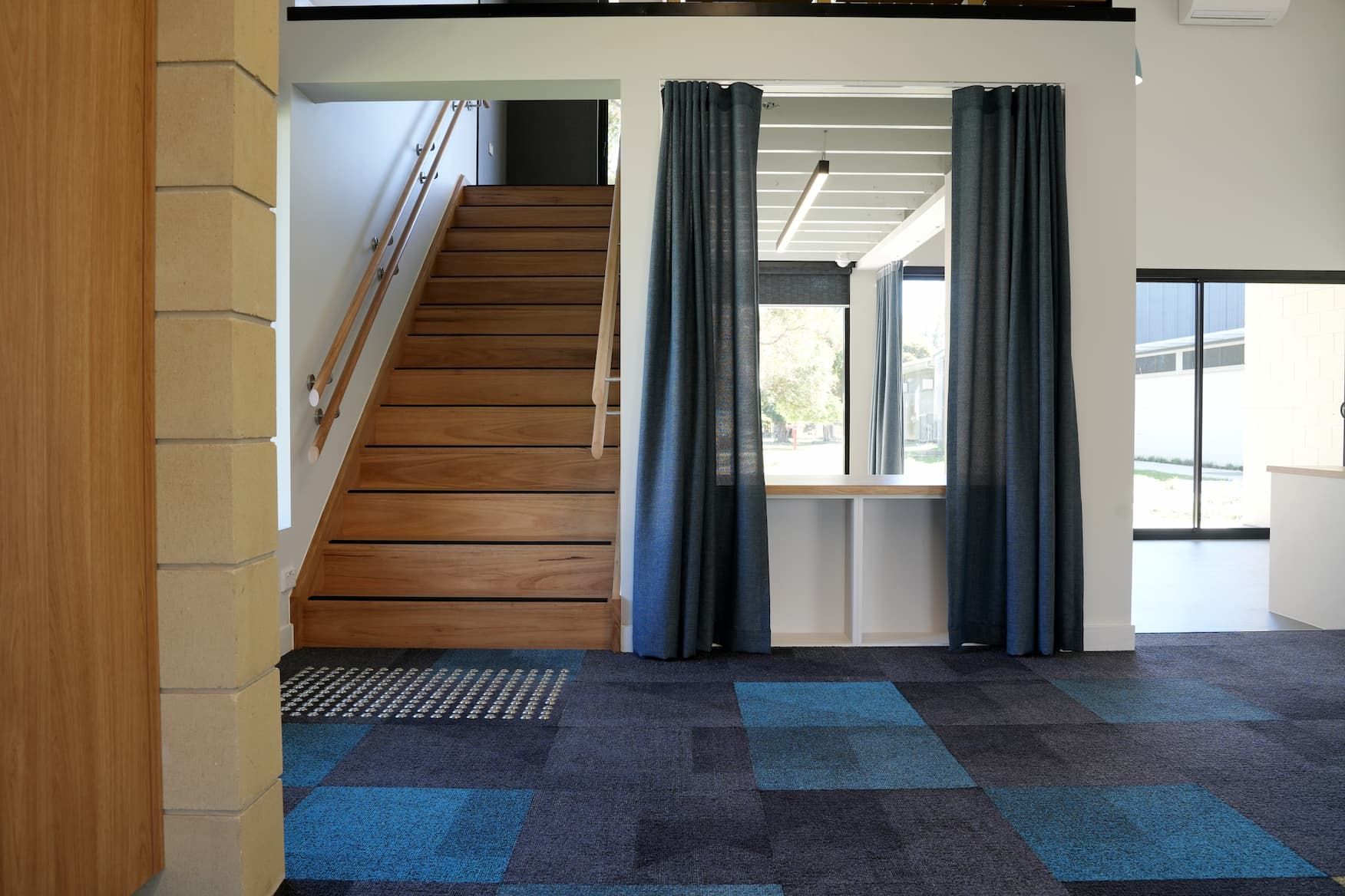 a wooden staircase with blue curtains behind it