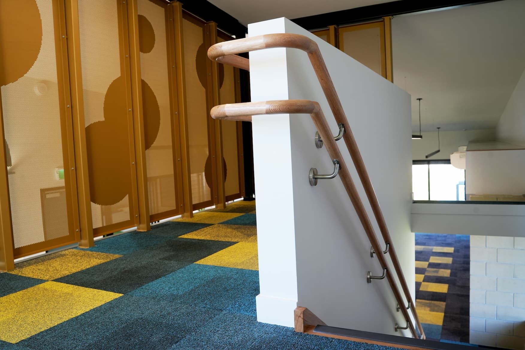 a staircase with a wooden railing and a yellow and blue carpet