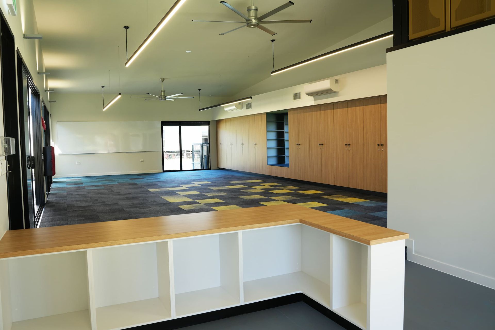 a large empty room with a ceiling fan and shelves