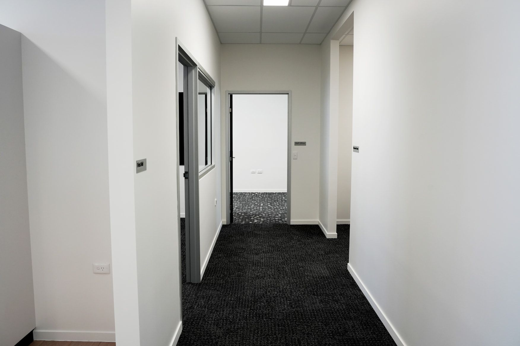 a hallway with black carpet and white walls