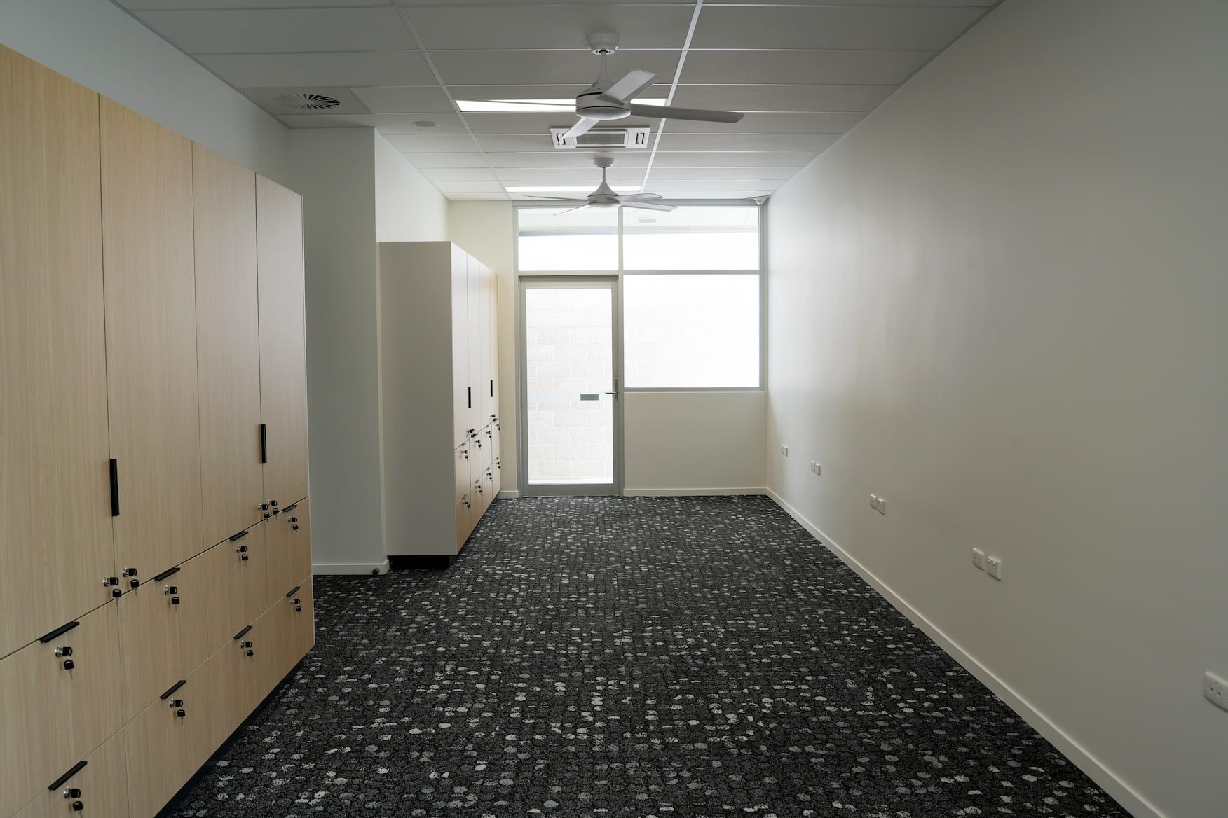 a long hallway with lockers and a ceiling fan