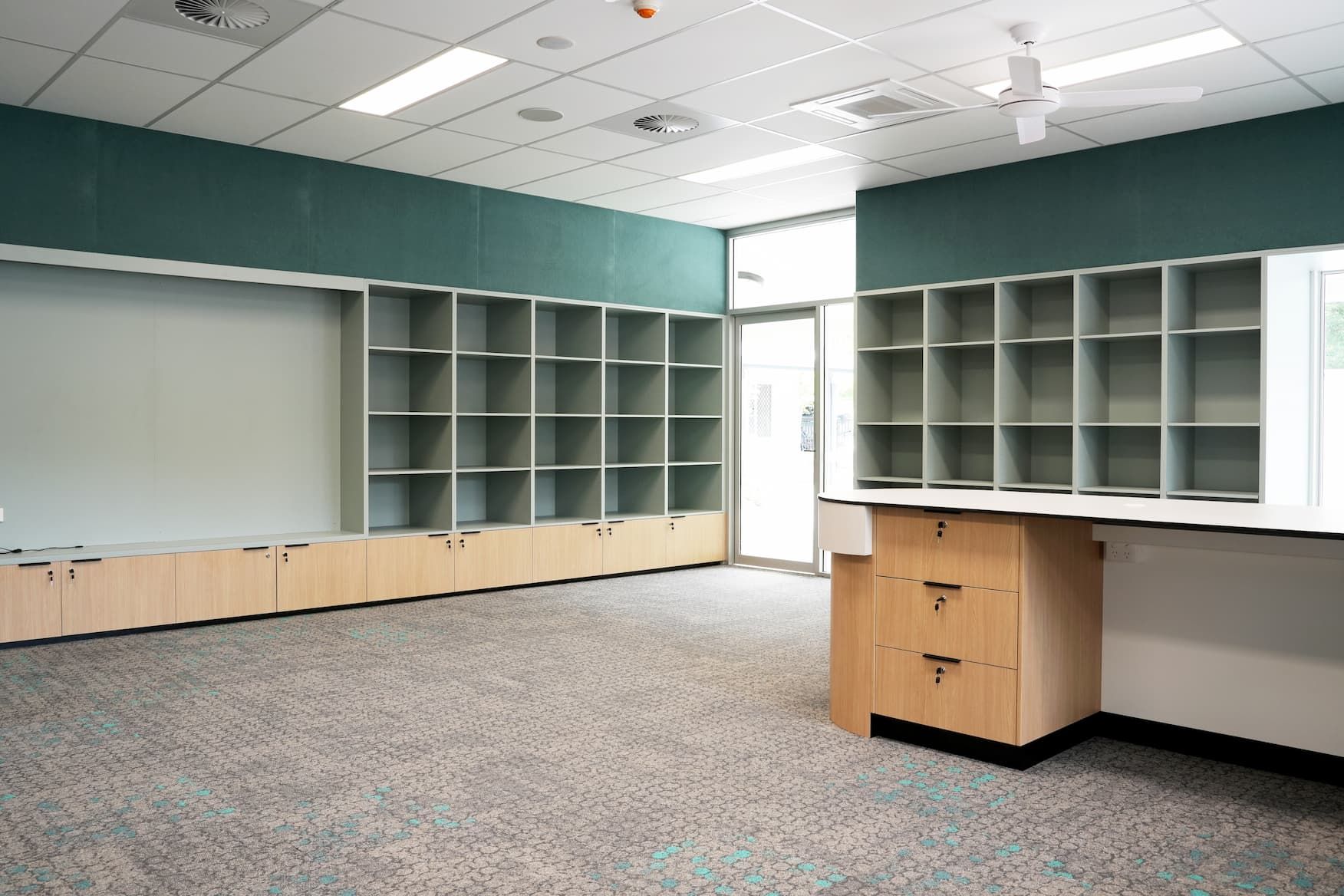 an empty room with shelves and drawers and a ceiling fan