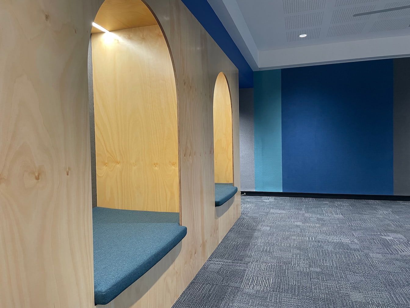 a hallway with a blue wall and a wooden bench