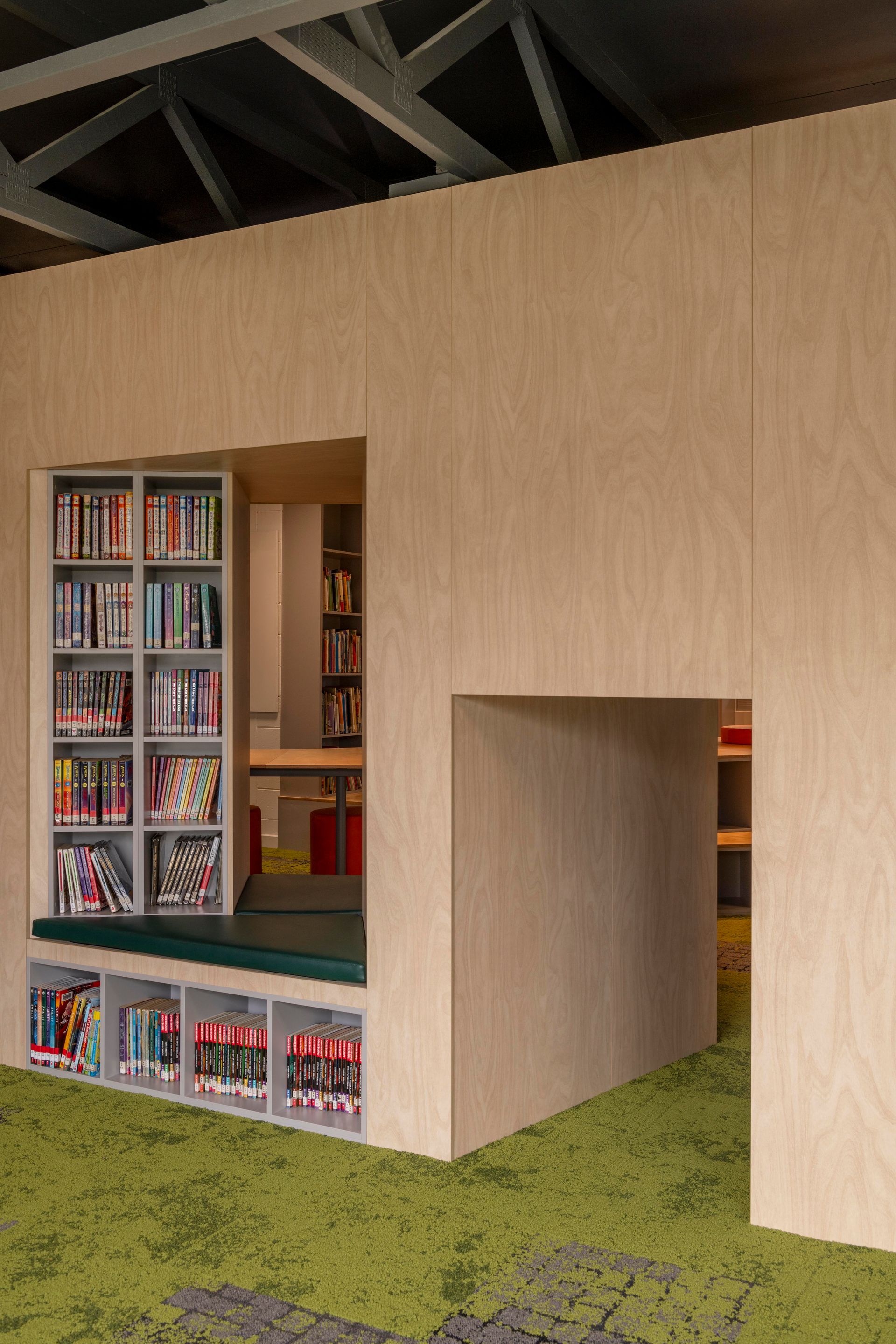 Wooden structure with a reading nook featuring bookshelves and a green carpet floor.
