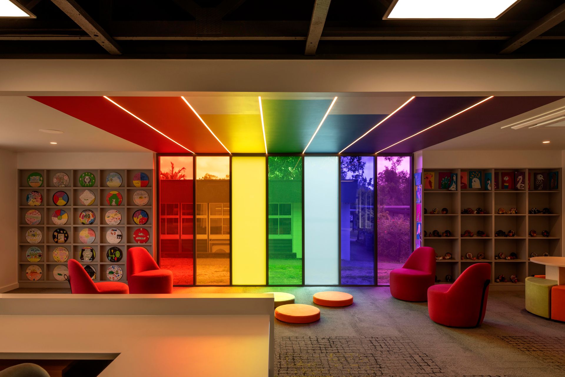 Rainbow-colored glass panels in a brightly lit room with seating and shelves of items.