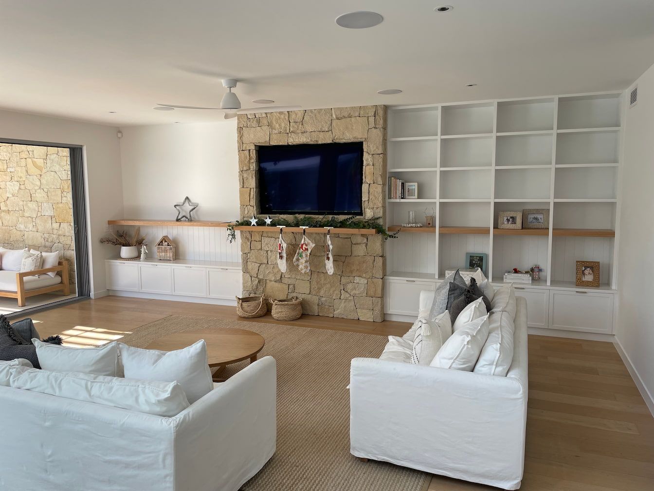 a Gold Coast living room with custom cabinetry a stone cladding fireplace and a flat screen tv 
