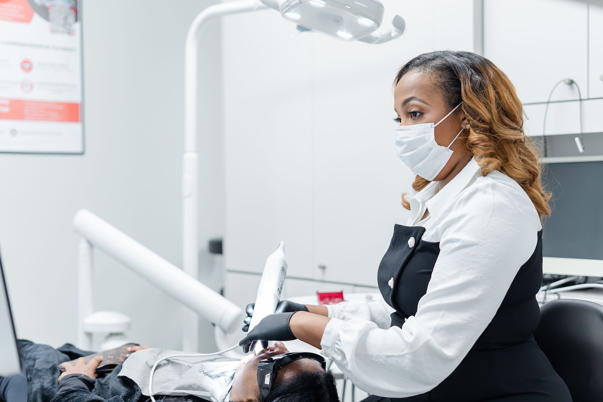 Dentist wearing a mask examines a patient in a dental chair at a clinic at DentCare Now, emergency dentist serving Fairfax, VA