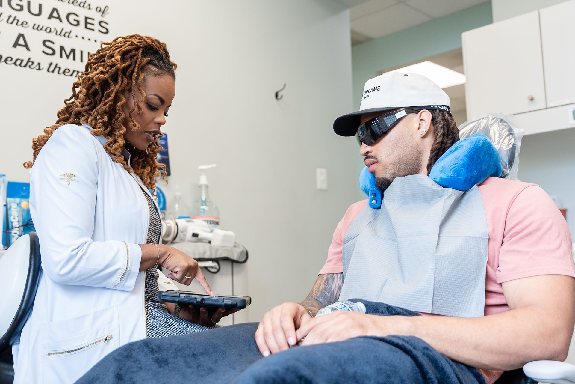 Dentist adjusting a blue bib for a seated patient in a clinic room at DentCare Now, emergency dentist serving Fairfax, VA