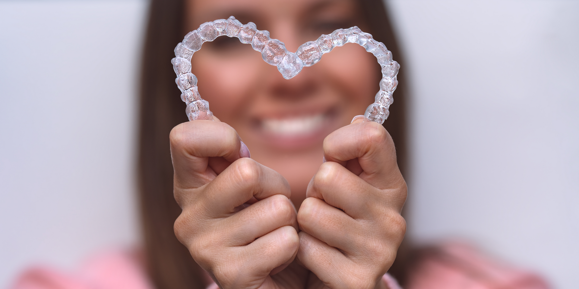 Hands holding a heart-shaped beaded frame around a smiling face