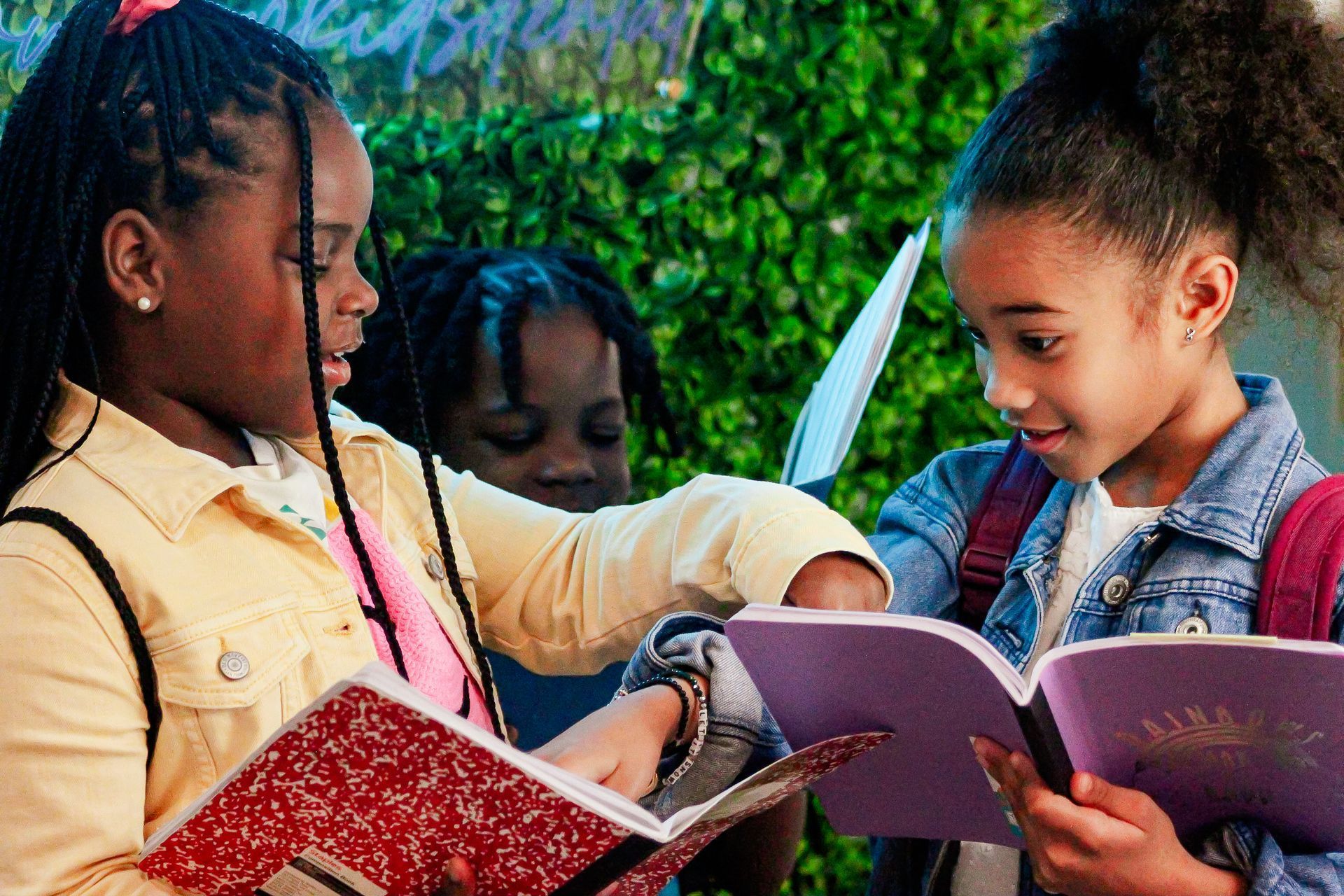 Children reading books together outdoors in a green garden