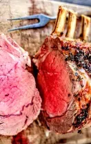 Sliced grilled rack of lamb with pink center on a wooden cutting board
