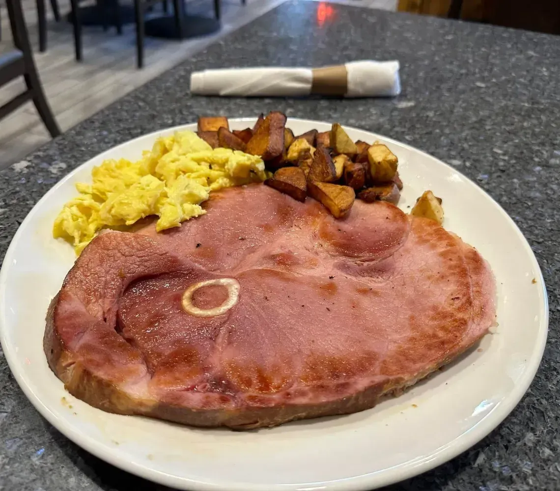 Hearty breakfast skillet with sausage, eggs, beans, tomatoes, and coffee on a wooden table
