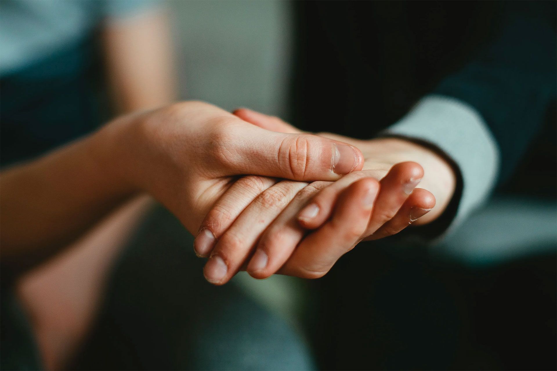A close up of a person holding another person 's hand.