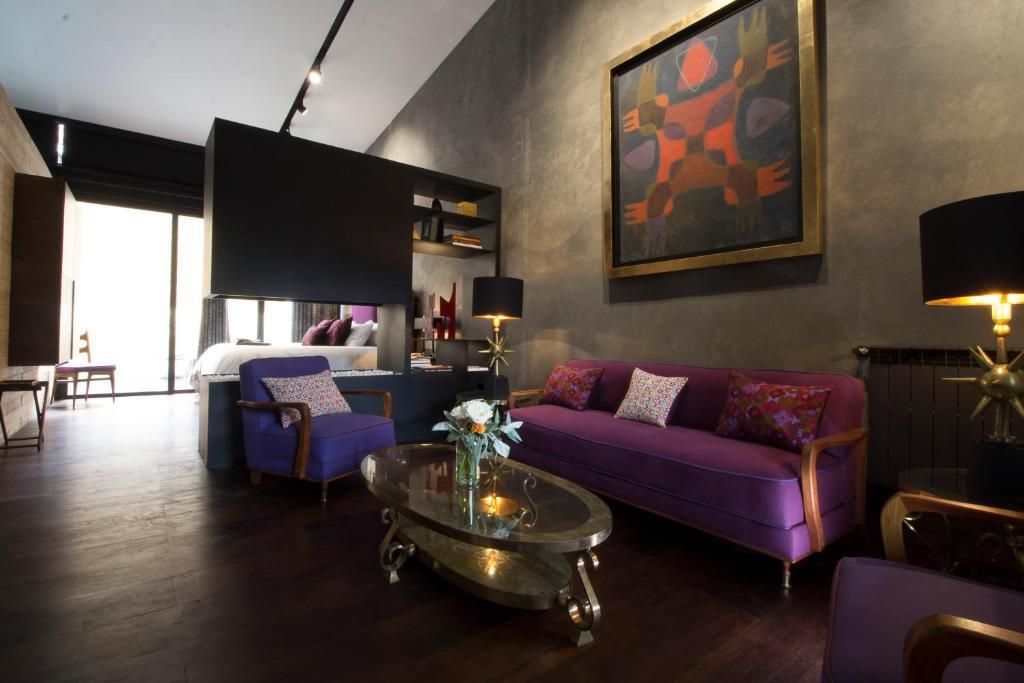 Una sala de estar  en el dormitorio con un sofá y sillas de color morado.